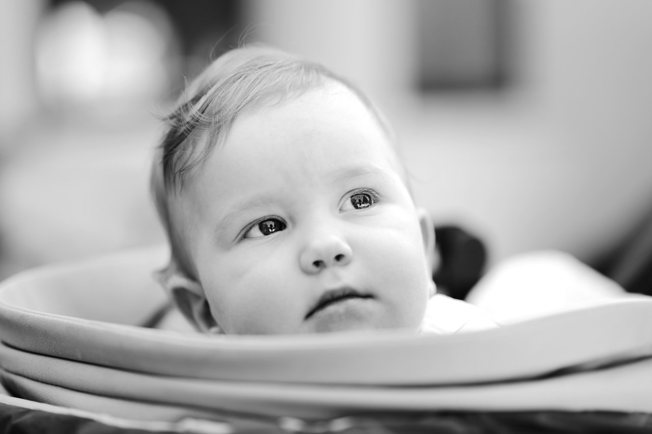 Crnobijeli portret prelijepe muške bebe sa znatiželjnim i nježnim izrazom lica.