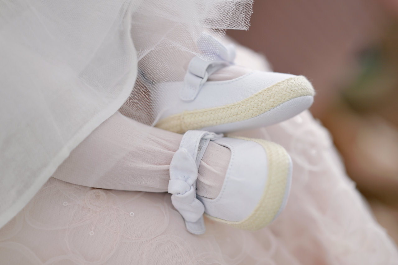 Detalj s krštenja u crkvi, u zagrebačkim Gajnicama - bijele cipelice ženske bebe.