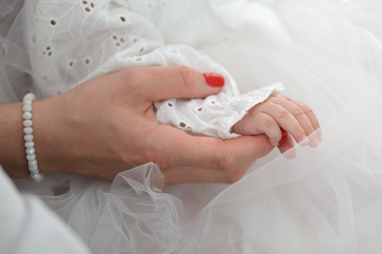 Detalj s obreda krštenja - bebina ručica drži majčinu ruku.