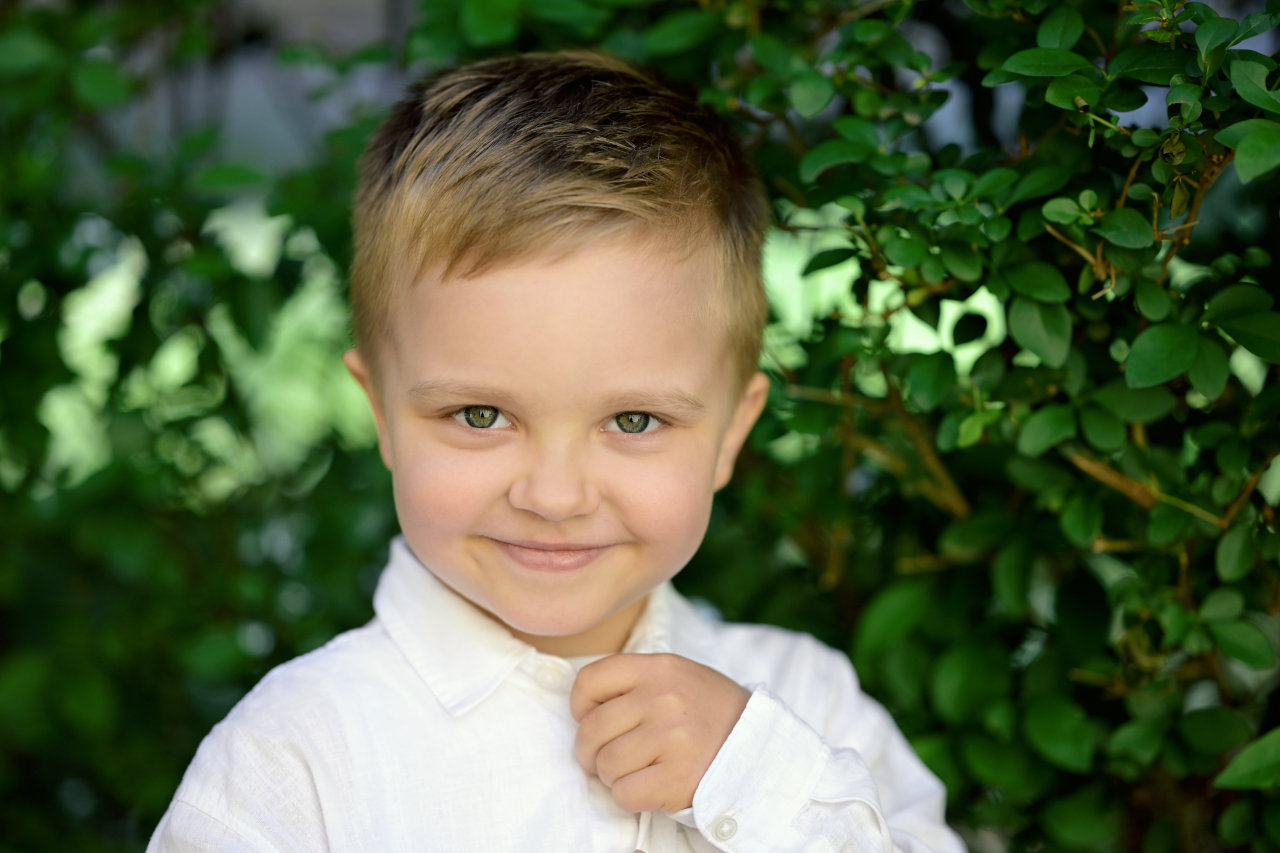 Portret nasmiješenog petogodišnjeg dječaka, s izražajnim zelenim očima.