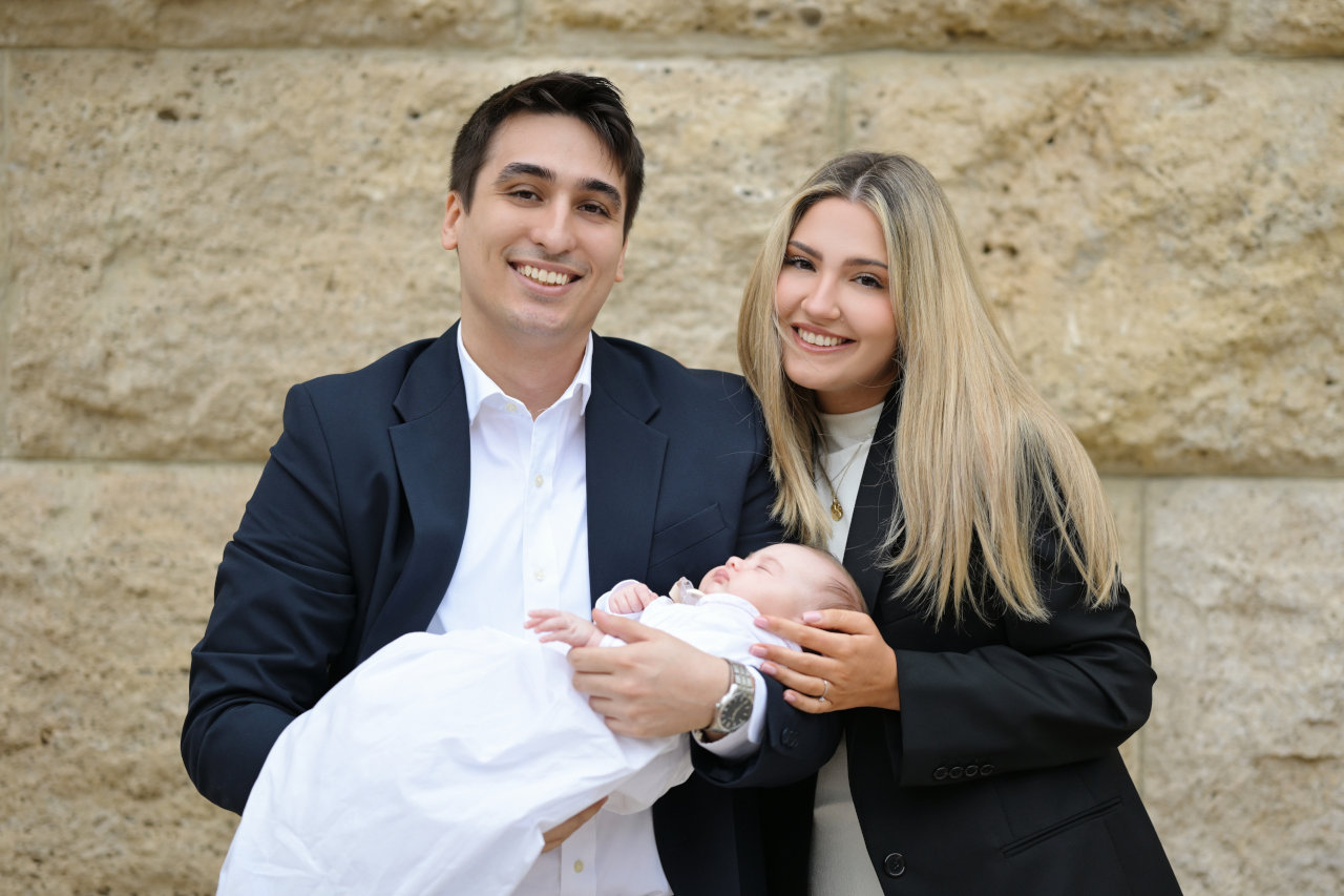 Nasmiješeni roditelji drže bebu ispred crkve Sv. Blaža u Zagrebu, obiteljski portret profesionalnog fotografa.