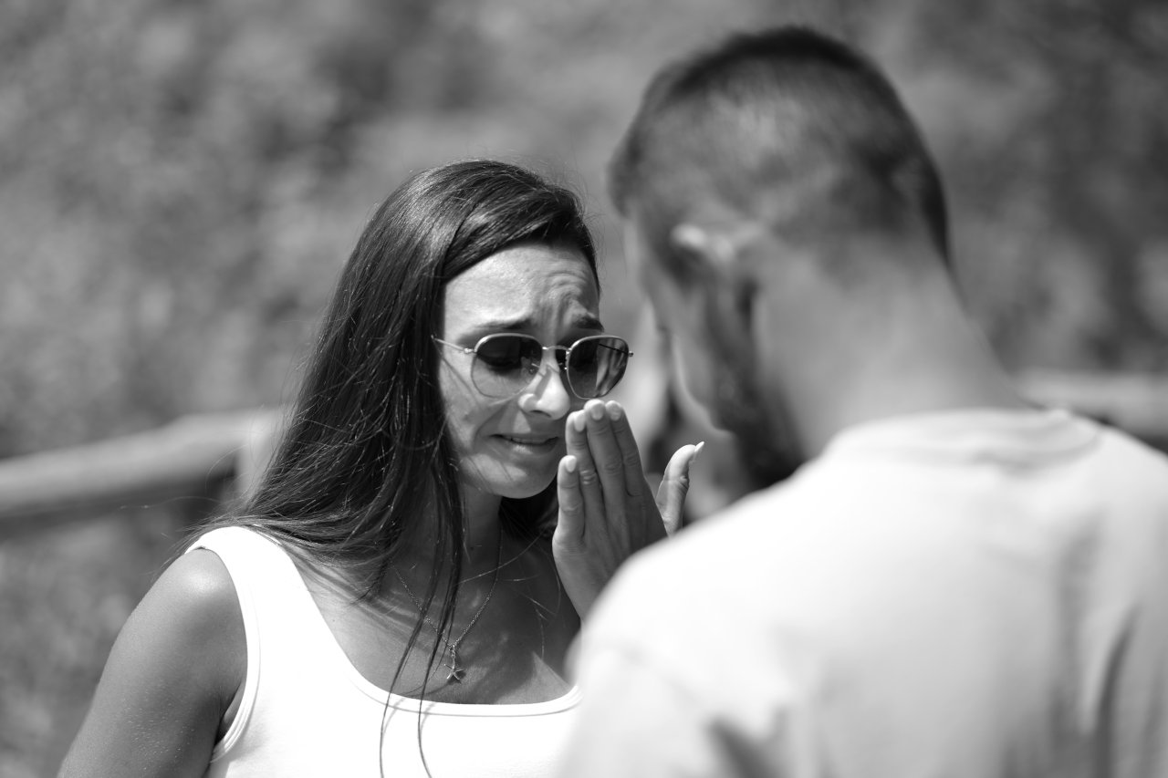 Crnobijela fotografija s fokusom na djevojku koja pokazuje snažne emocije prilikom zaruka i prosidbe na Plitvicama.