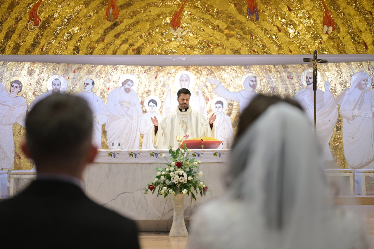 Vjenčanje u Zagrebu – mladenci pred oltarom punim zlatnih detalja tijekom ceremonije koju predvodi svećenik.