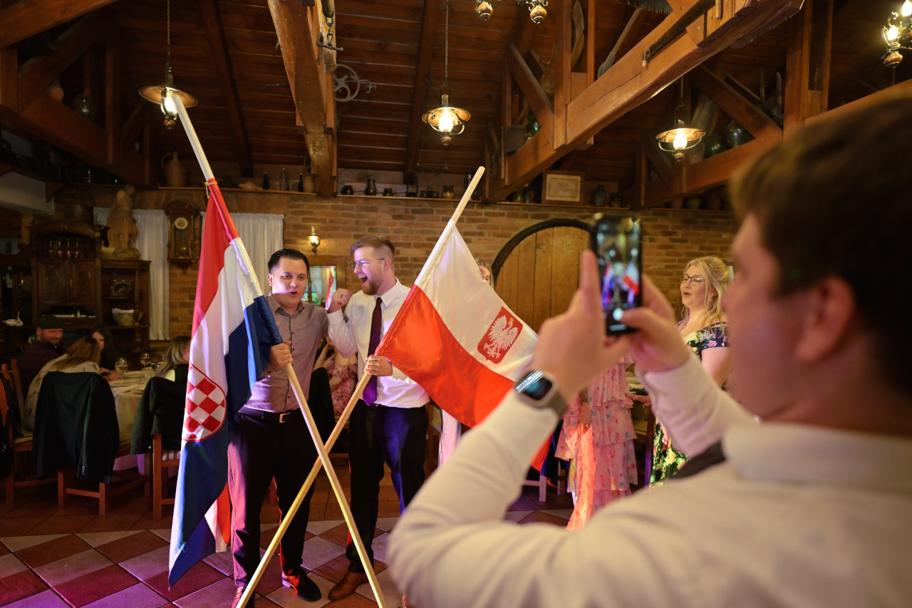 Proslava vjenčanja u Zagrebu; dva mladića u sali drže poljsku i hrvatsku zastavu.