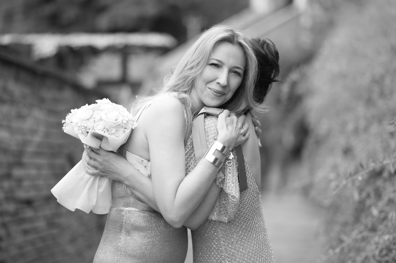 Crnobijela fotografija emotivnog zagrljaja kume i mladenke na zagrebačkom Gornjem gradu.